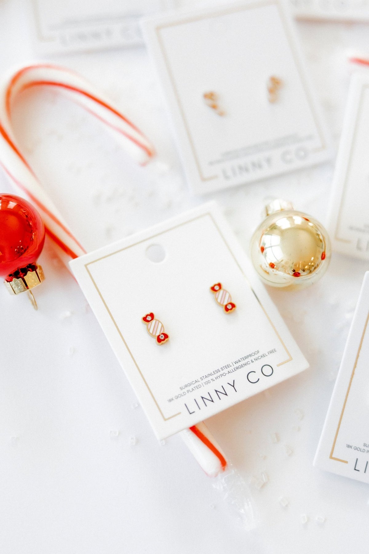 LINNY CO Taffy screwback stud earrings for kids & little girls — hypoallergenic, waterproof stainless steel with secure screwback backs, flat-lay styling.