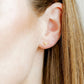 LINNY CO Texas Steer Gold screwback stud earrings for kids & little girls — hypoallergenic, waterproof stainless steel with secure screwback backs, shown on model.