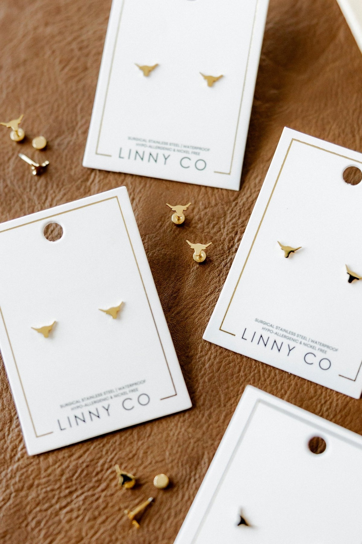 LINNY CO Texas Steer Gold screwback stud earrings for kids & little girls — hypoallergenic, waterproof stainless steel with secure screwback backs, shown on model.